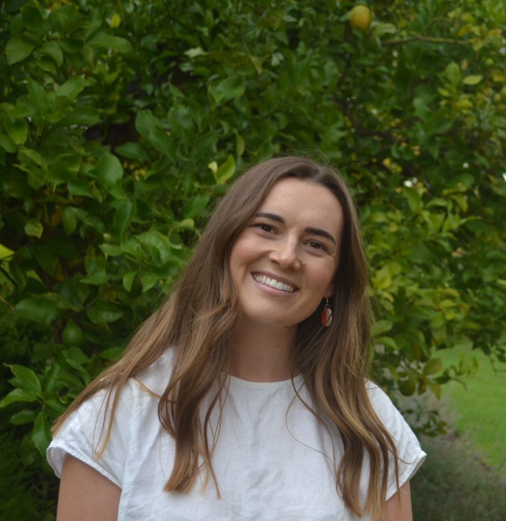 Portrait of a smiling Gabby in front of a green tree